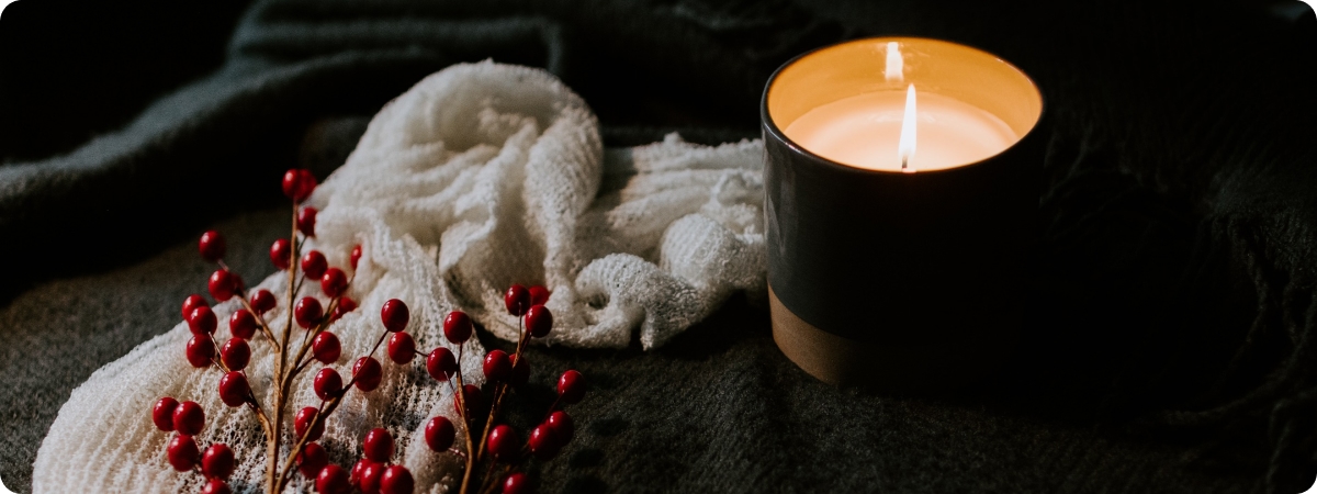 A large beautiful candle surrounded by eucalyptus twigs
